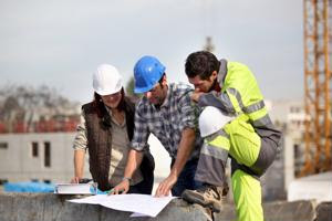 Three workers examine a building plan.