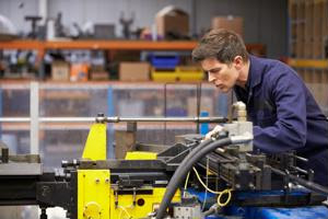 An employee uses a heavy machine on a shop floor.